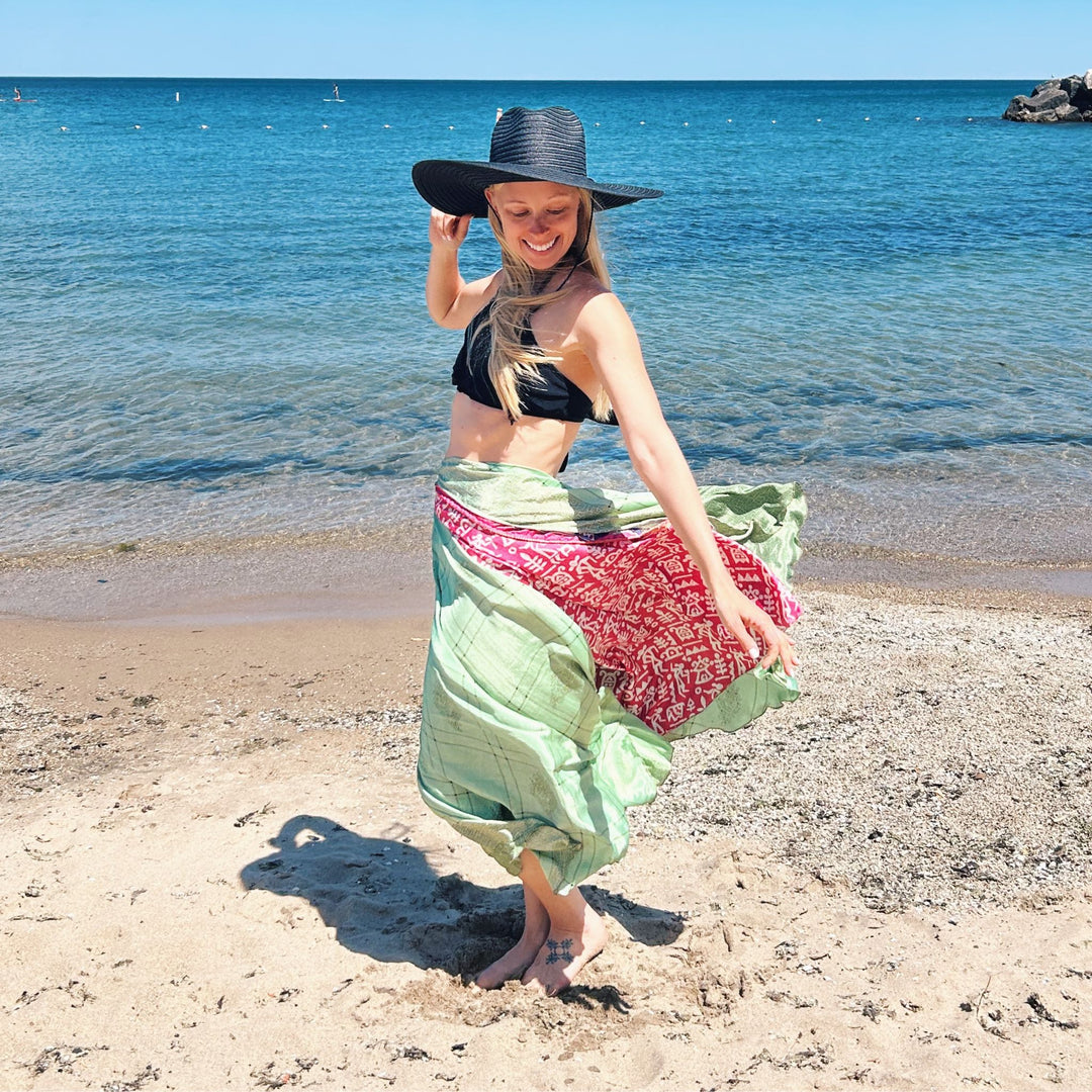 A girl wearing a light green sari wrap skirt on a beach