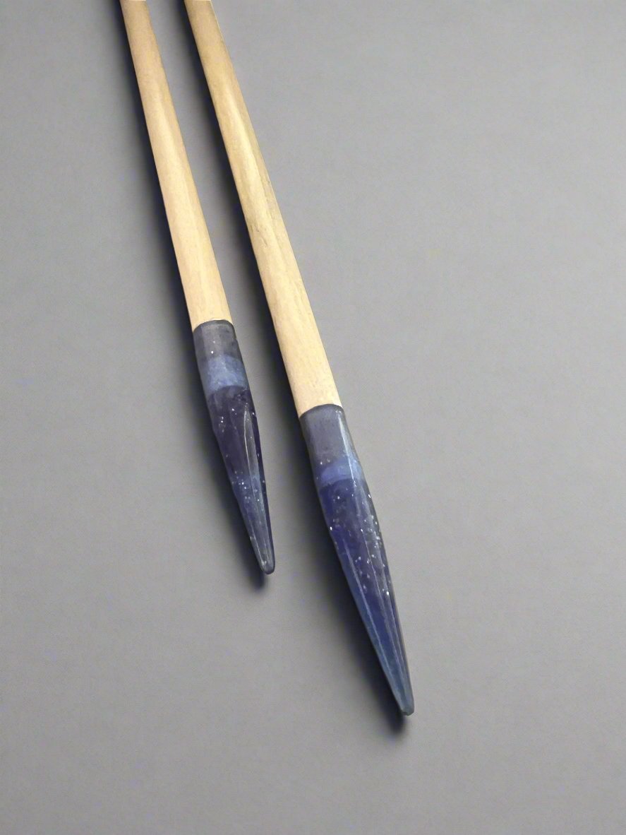 Two wooden brushes with blue-tinted tips against gray background.