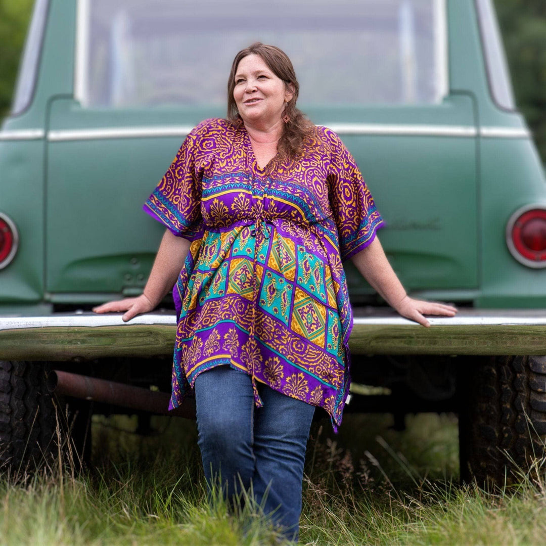 Woman leaning against a car wearing a purple short kaftan