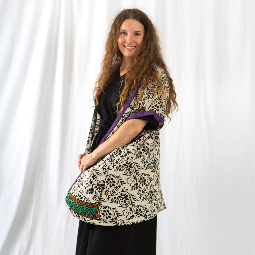 A woman smiling wearing amara short duster against a white curtain background.