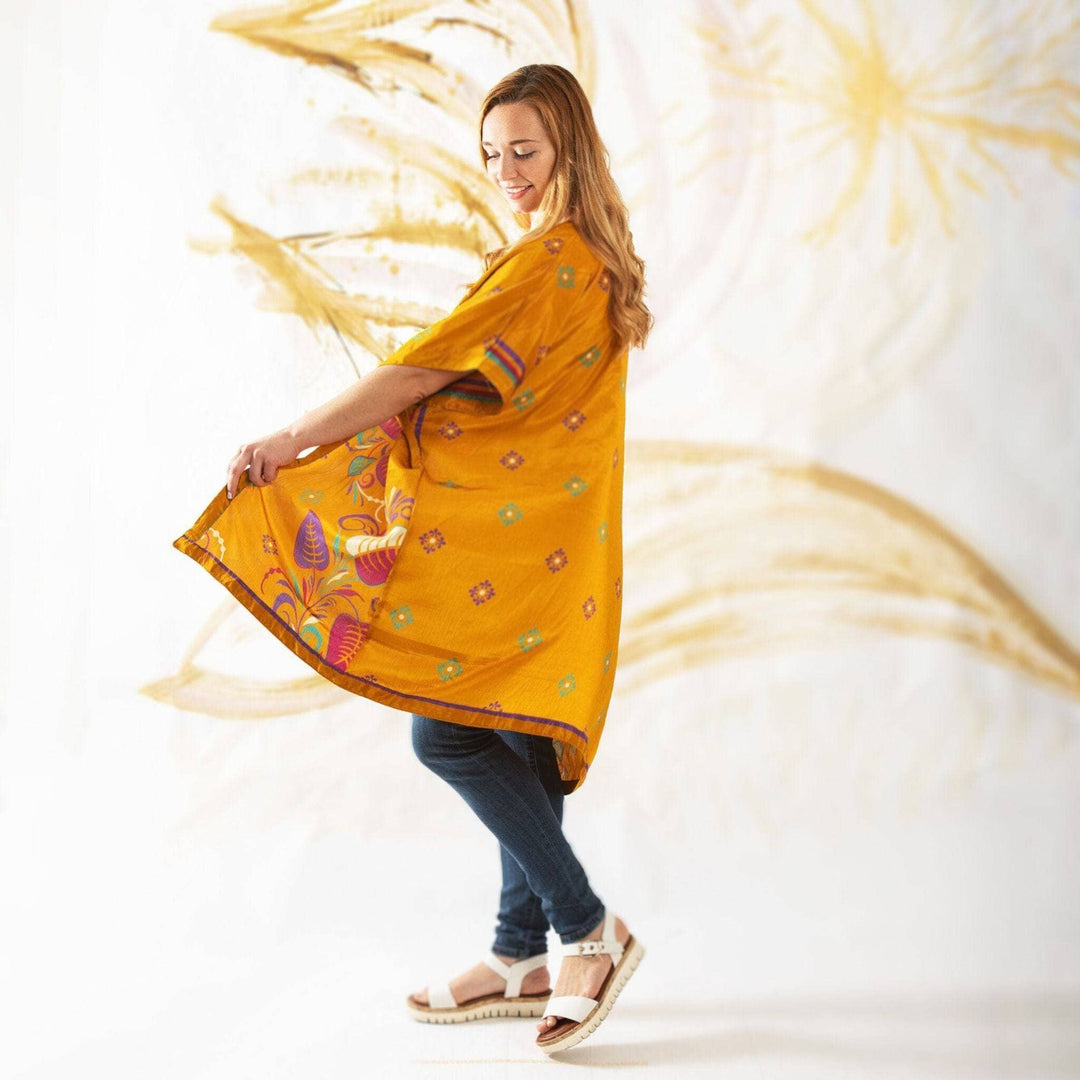 Girl wearing an orange-yellow amara duster standing in front of a painting