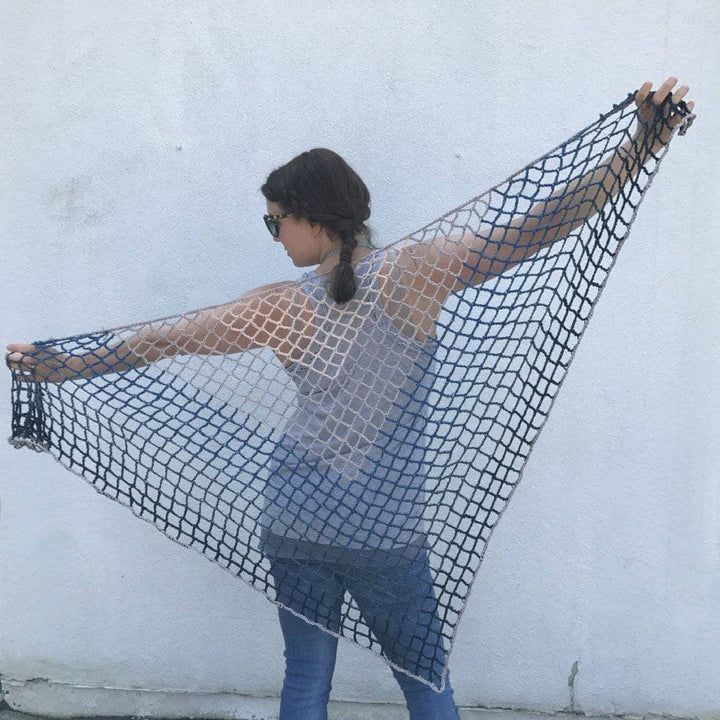 Woman holding a Blue Jay Triangle Scarf behind her back and standing in front of a white wall