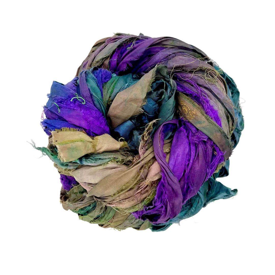 A variegated skein of blue, purple, and green sari silk ribbon on a white background