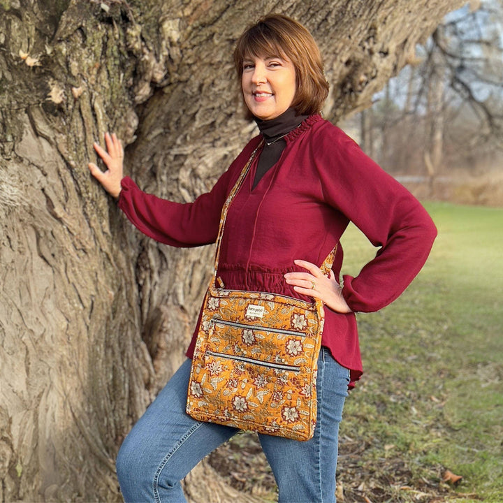 Woman standing next to a tree wearing an yellow ochre bag