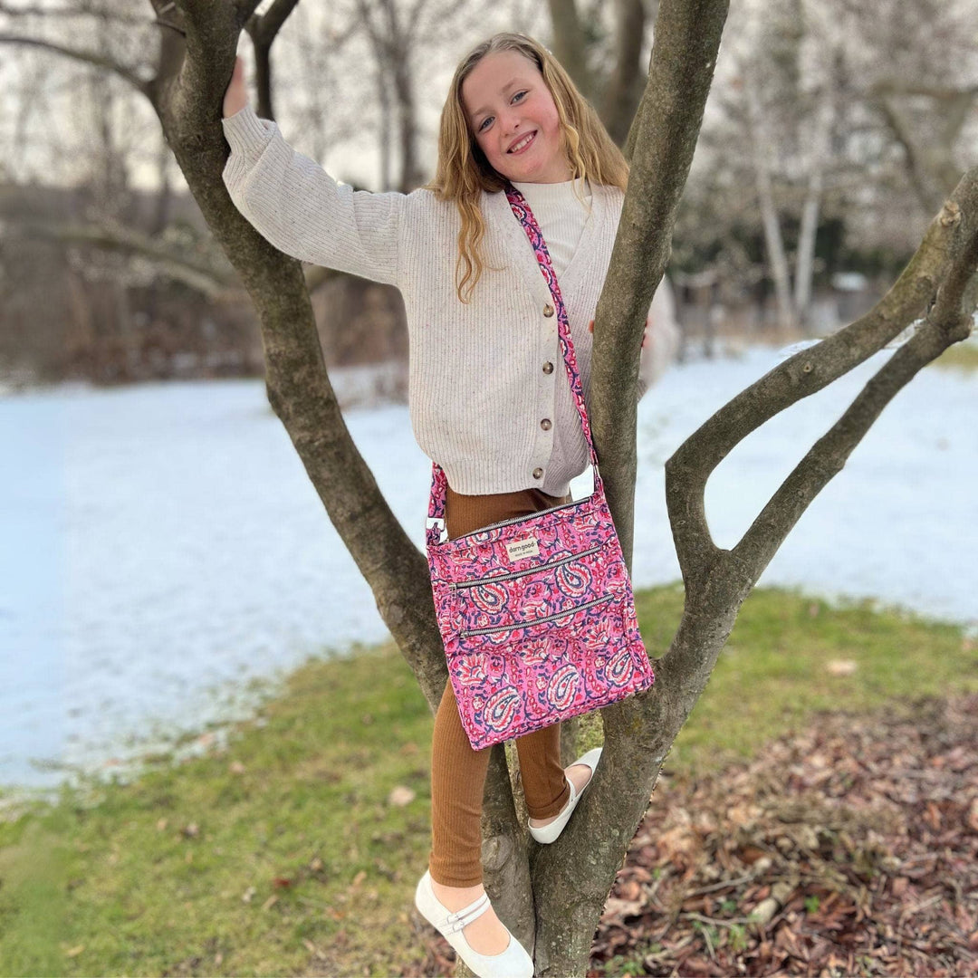 Young girl in a tree wearing a pink bag