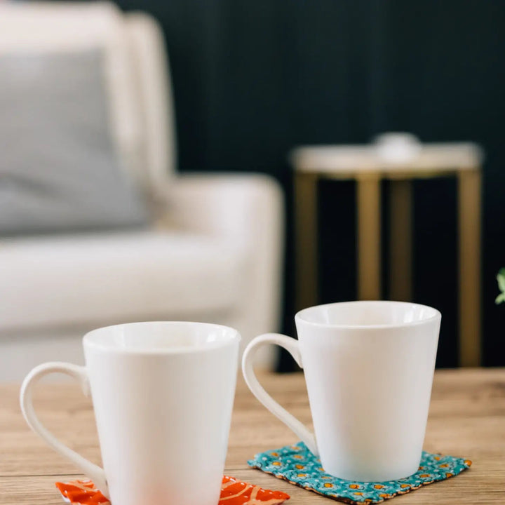 Two white coffee mugs sitting on two of the kantha coasters.