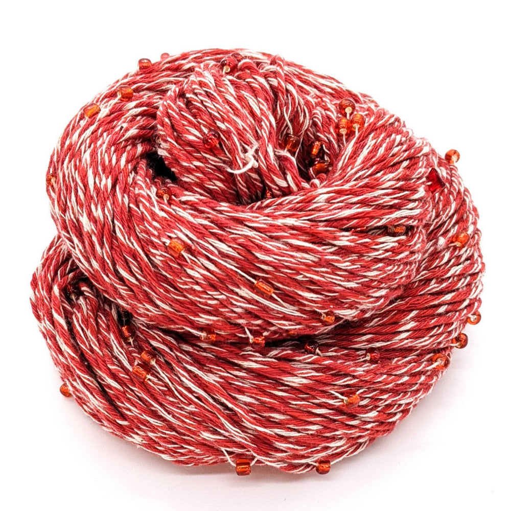 A coiled skein of red and white yarn with orange beads.