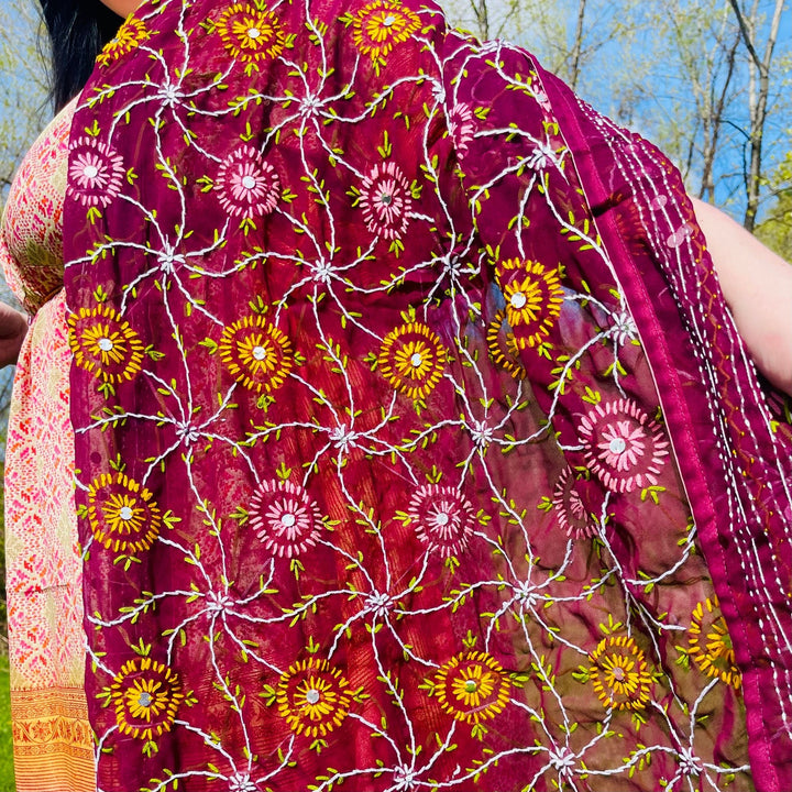 Close-up of an embroidered maroon shawl with vibrant floral patterns.