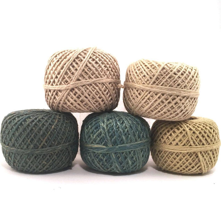 5 cakes of yarn in dark green, medium green, light green, dark tan, and light tan on a white background