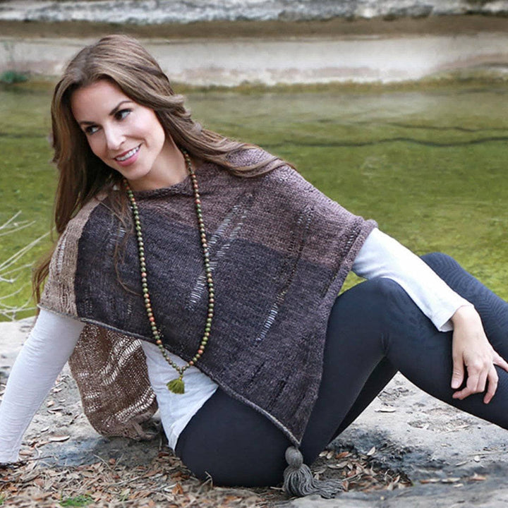 woman smiling wearing a brown poncho