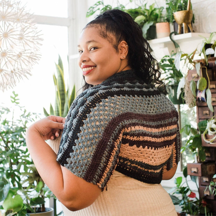 model wearing ebb and flow shrug in winter frost with potted greenery in the background.