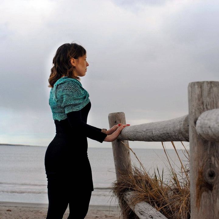 Model wearing emerald bay shawl with the ocean in the background.