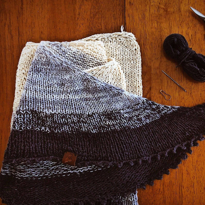 White, grey and black shawl on a wood background