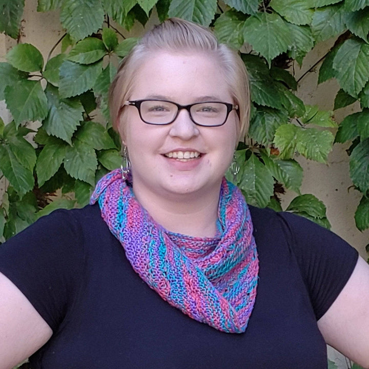 Woman wearing a black shirt outside with a pink, teal and blue shawl on