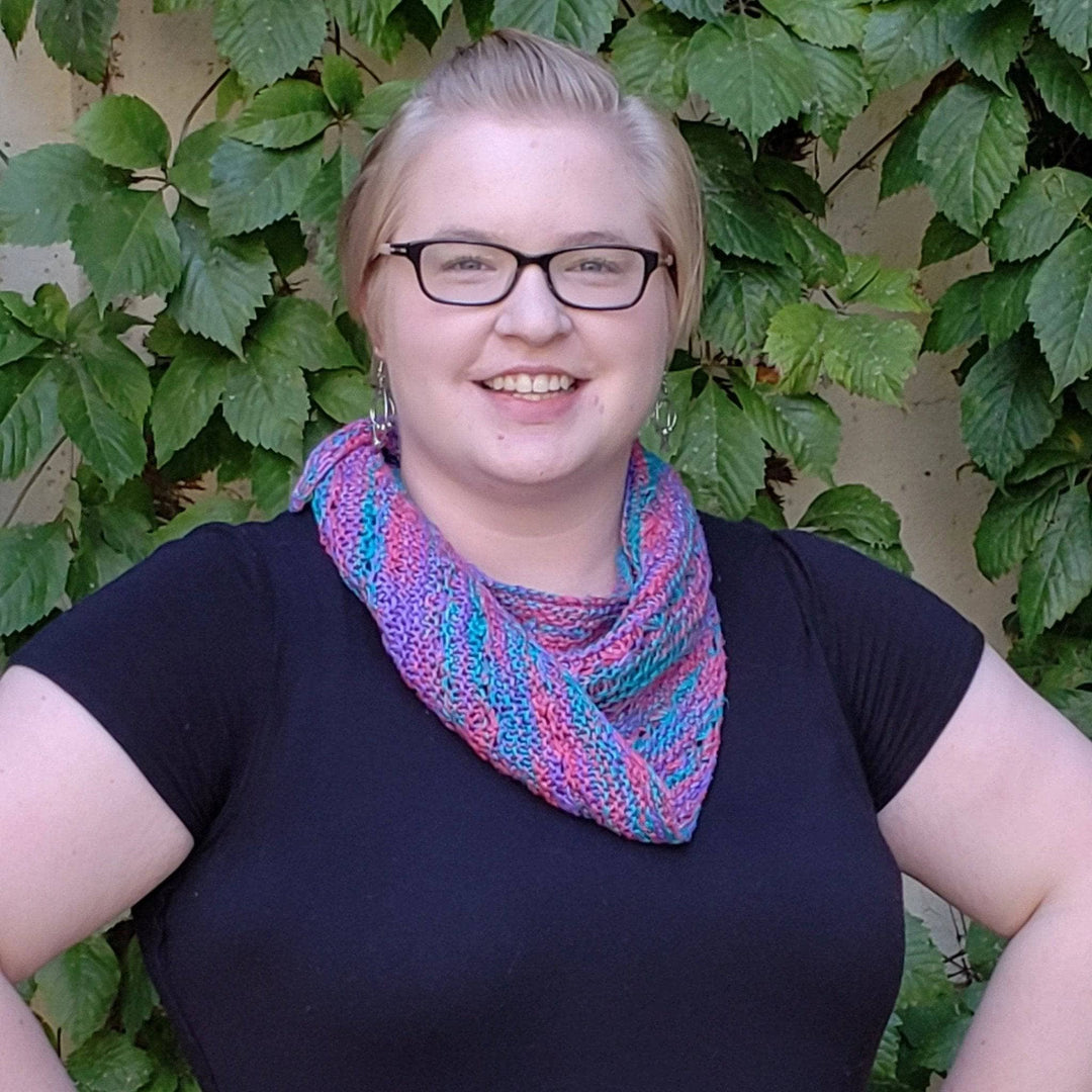 Woman wearing a black shirt outside with a pink, teal and blue shawl on