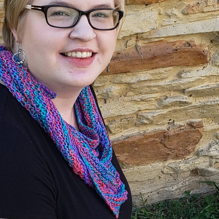 Woman wearing a black shirt outside with a pink, teal and blue shawl on