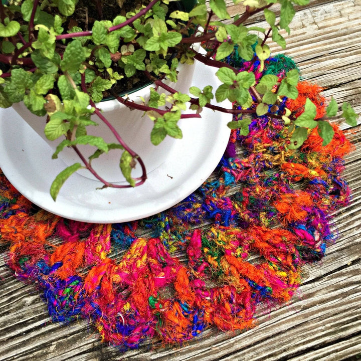 close up of colorful Doily with a flower pot on top of it