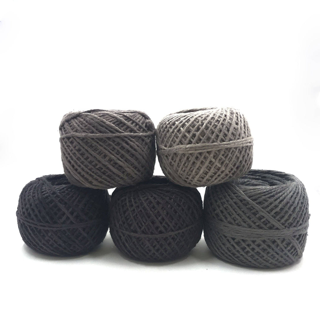 five yarn cakes of different colors over a white background