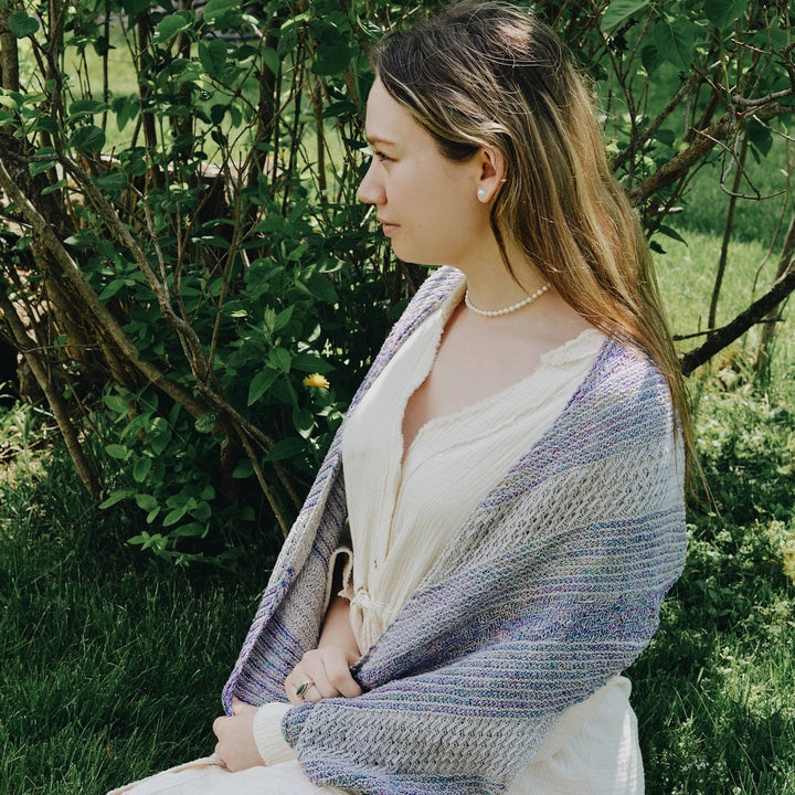 model sitting wearing frosted forest wrap in blue and white with greenery in the bakground.