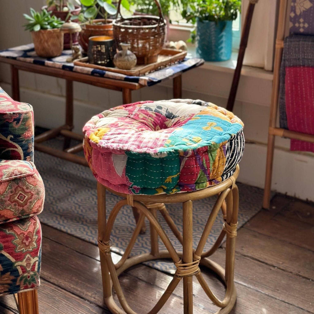 A patchwork pouf pillow on top of a bamboo ottoman. 