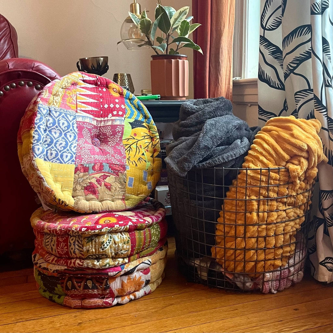 Three One of a Kind Hand Embroidered Pouf pile on the floor. 