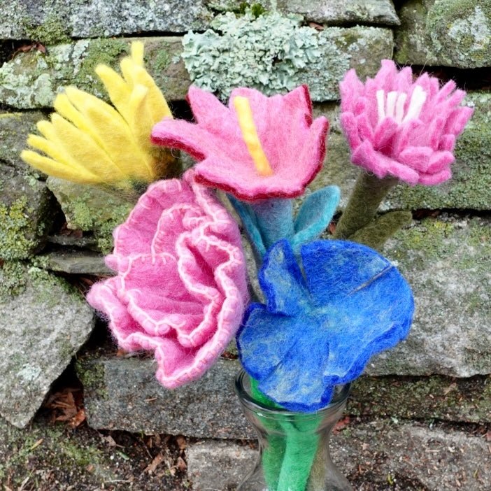 Felted flowers in pink, blue, and yellow arranged in a glass vase.