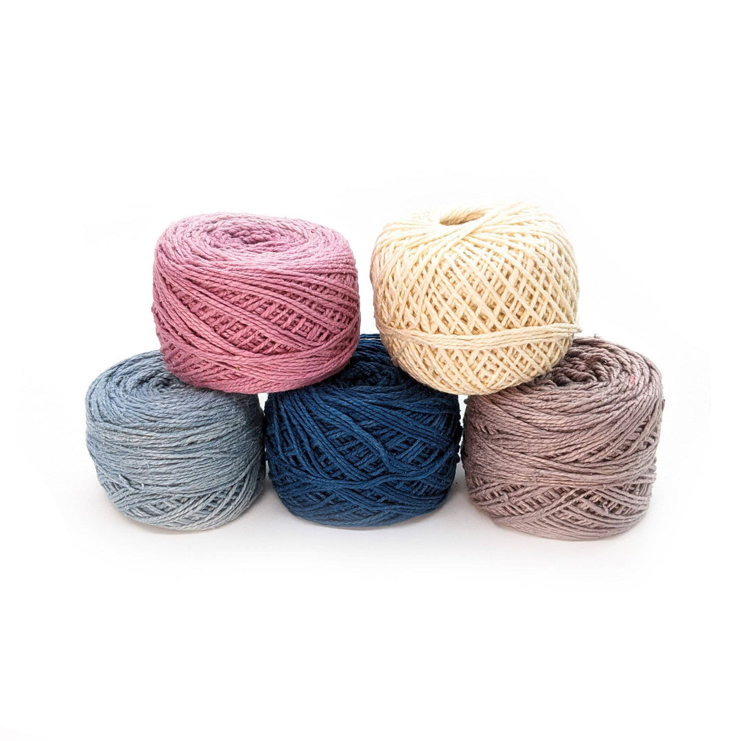 DK weight herbal dyed yarn pack in colorway winter frost in front of a white background. From left to right: Light blue, pink, dark blue, cream, light grey.