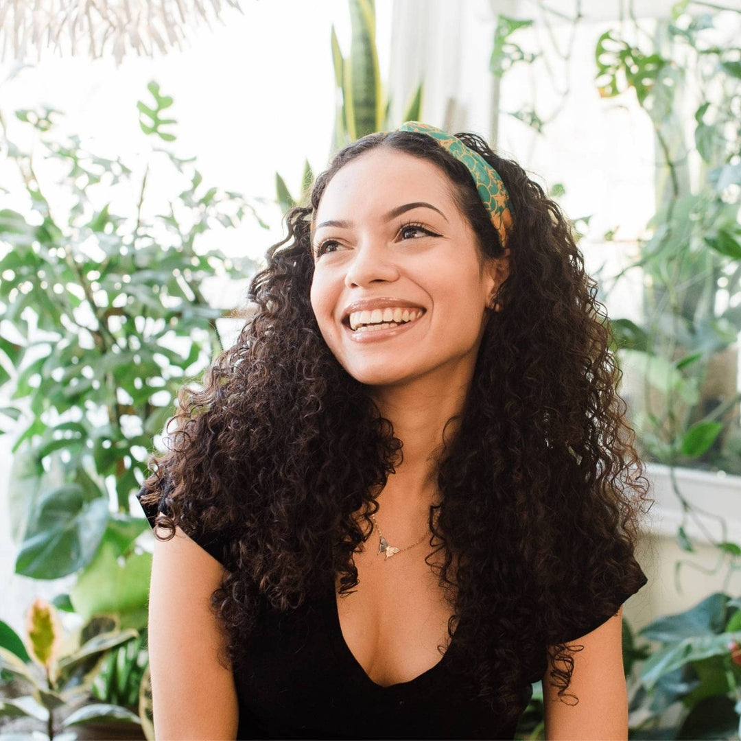 Model is wearing a green kameela knot headband in her hair. 