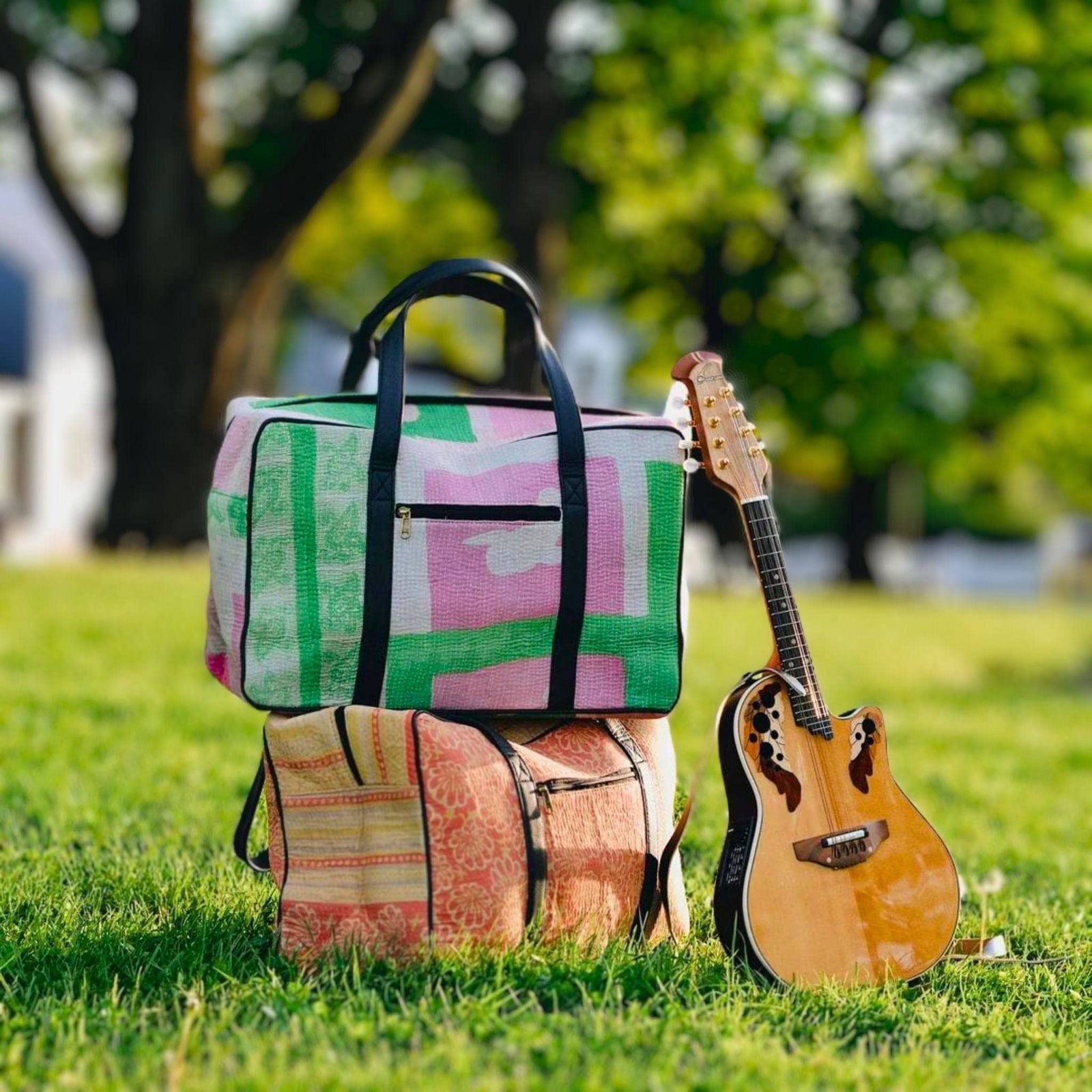 2 Colorful kantha duffle bags stacked on eachother in a park.