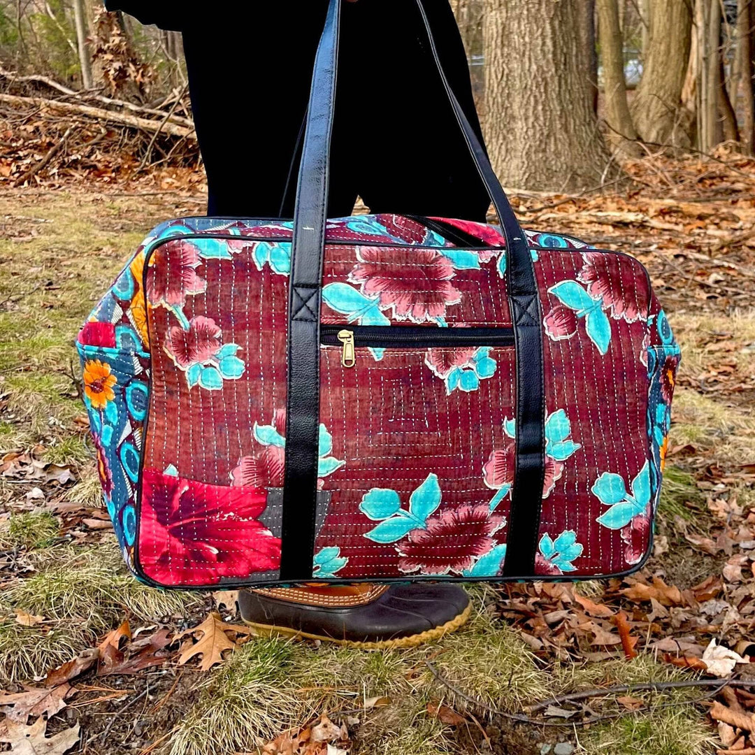 A model holding a purple Kantha Duffle Bag with Light Blue and Lavender Flower Patterns on it.