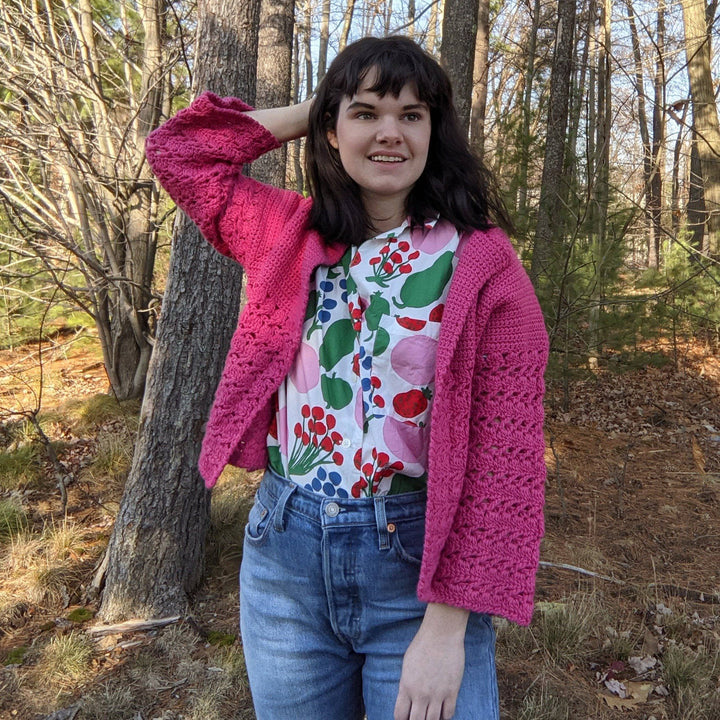 a person wearing a pink cardigan outside