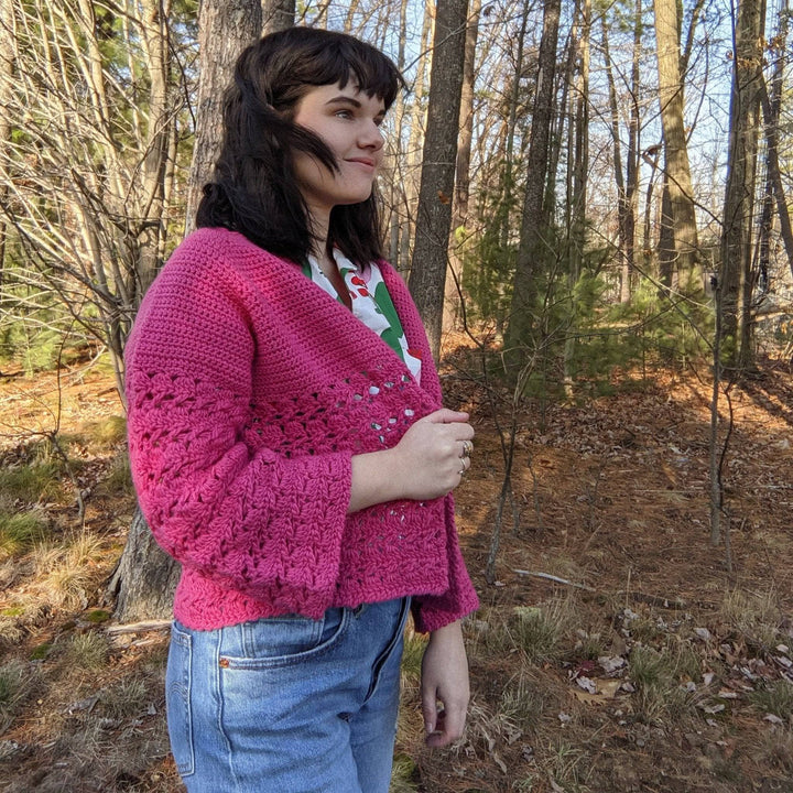 a person wearing a pink cardigan outside