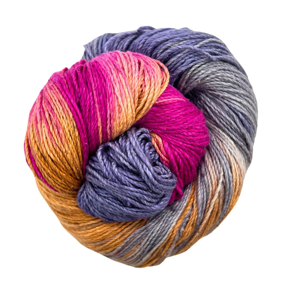 A colorful yarn in hues of pink, purple, and orange twisted together in a vibrant skein