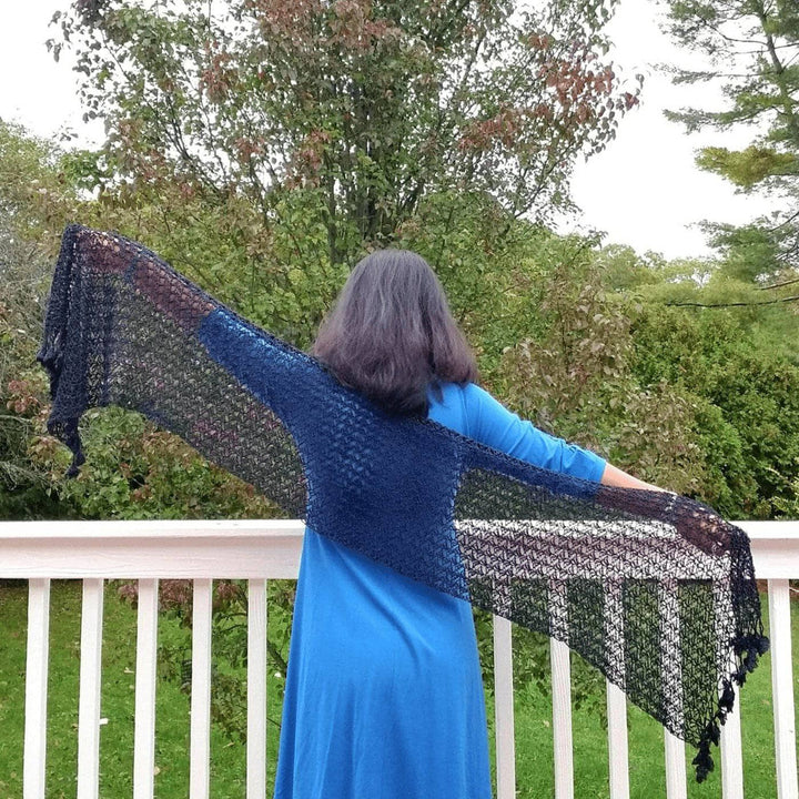 Woman wearing a blue shirt outside holding a black shawl 