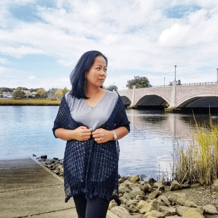 Woman wearing a grey shirt outside with a black shawl on