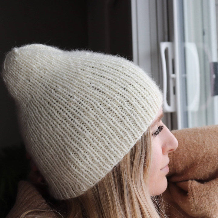 A person wearing a white knit beanie 