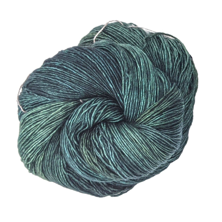 skein of tonal green yarn in front of a white background.