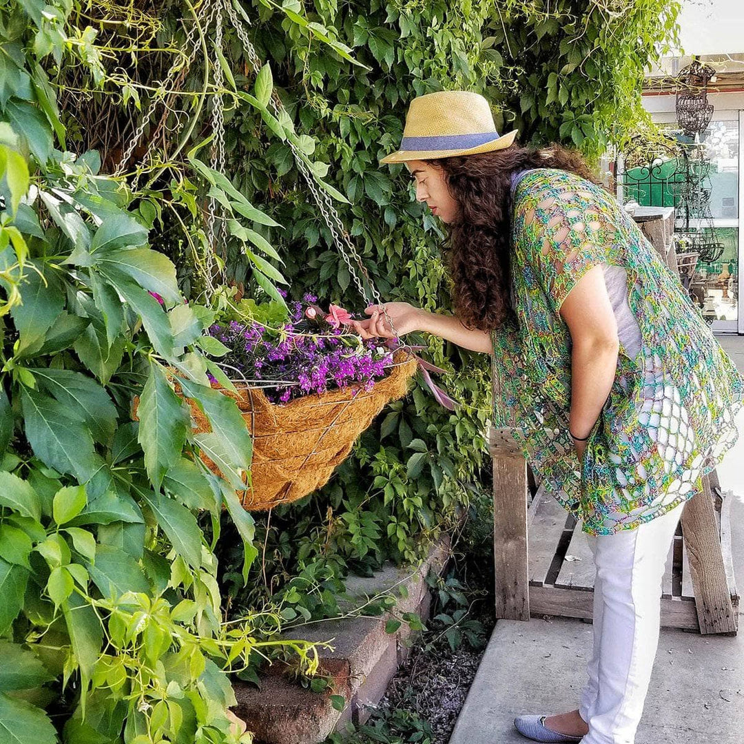 woman wearing a green poncho looking at flowers