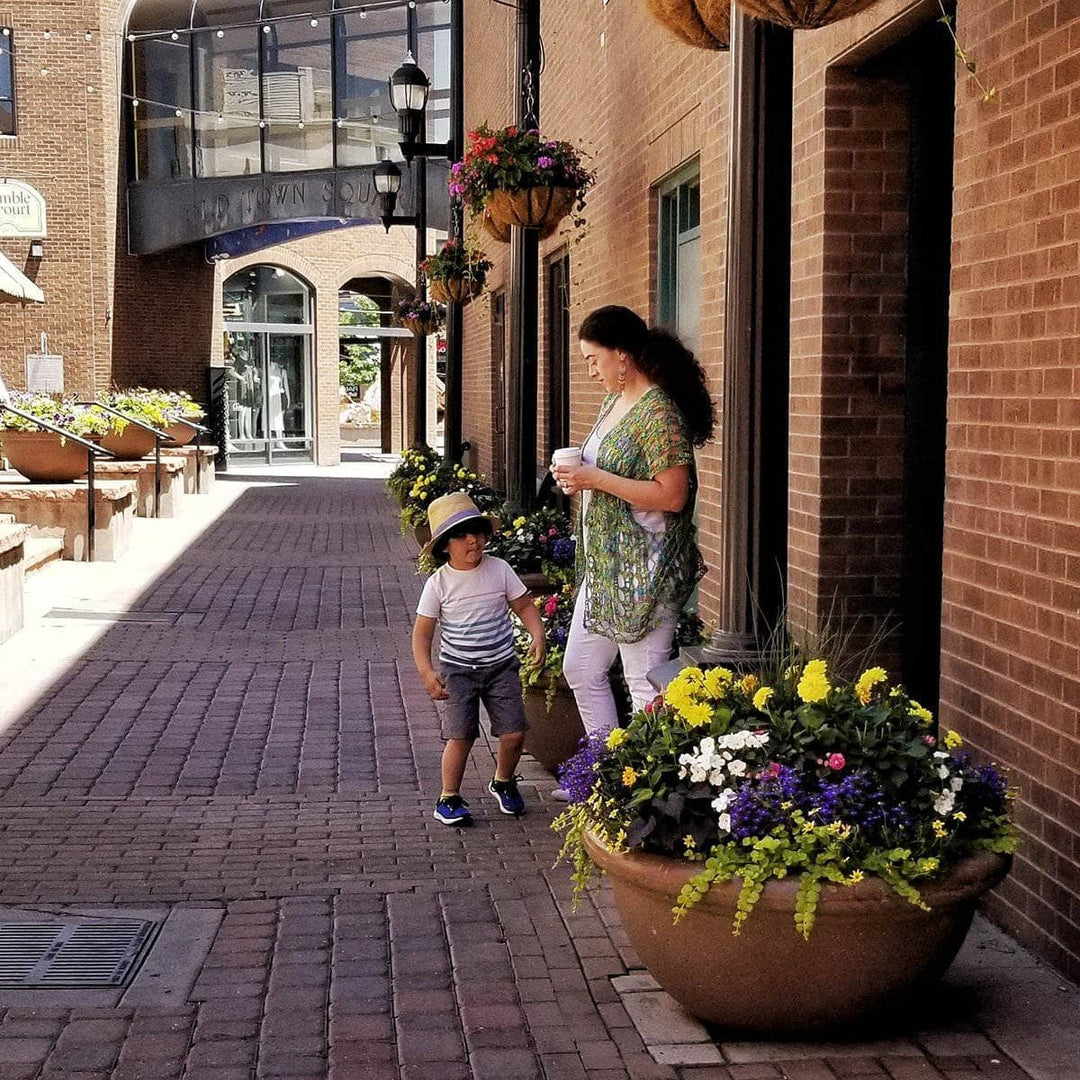 woman wearing a green poncho with a child next to her standing in a street