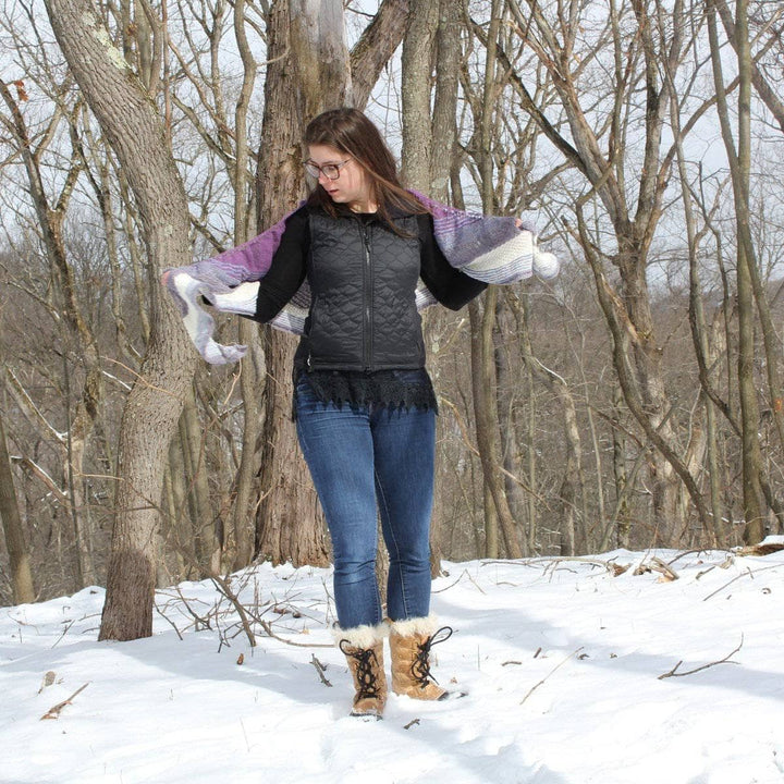  woman holding a purple white and pink shawl with snow in the background