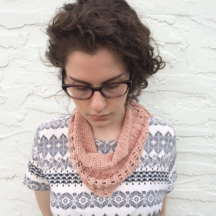 close up woman looking down wearing a small pink scarf 