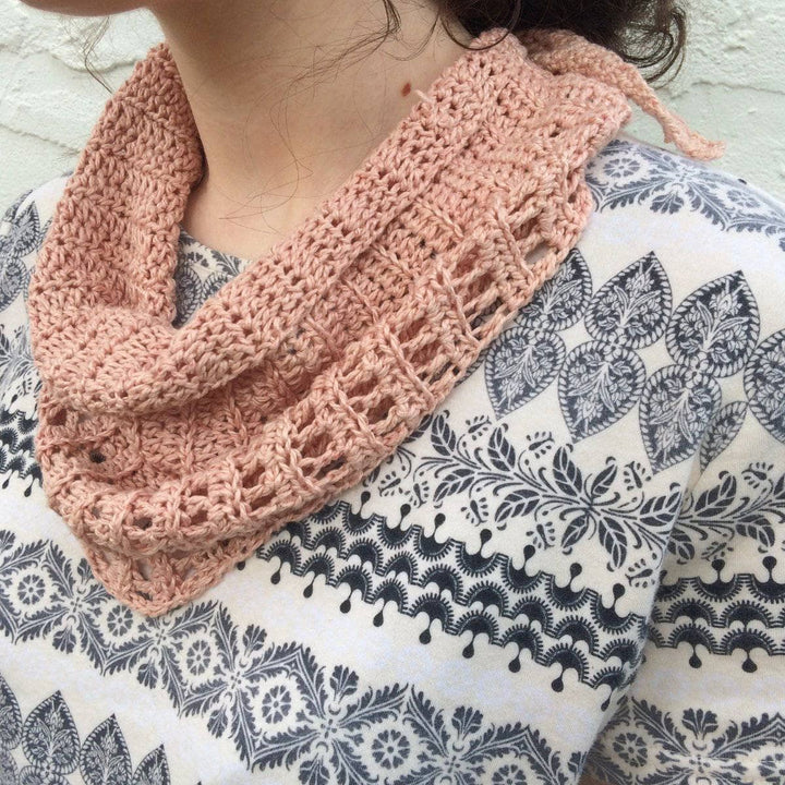 close up woman looking down wearing a small pink scarf 