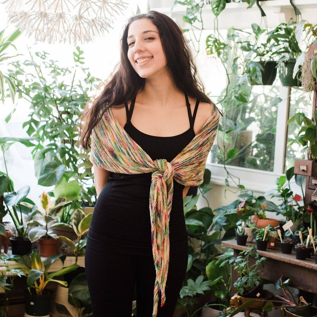 Model wearing unicorn cloud neon pop shawl tied at the front with potted greenery in the background