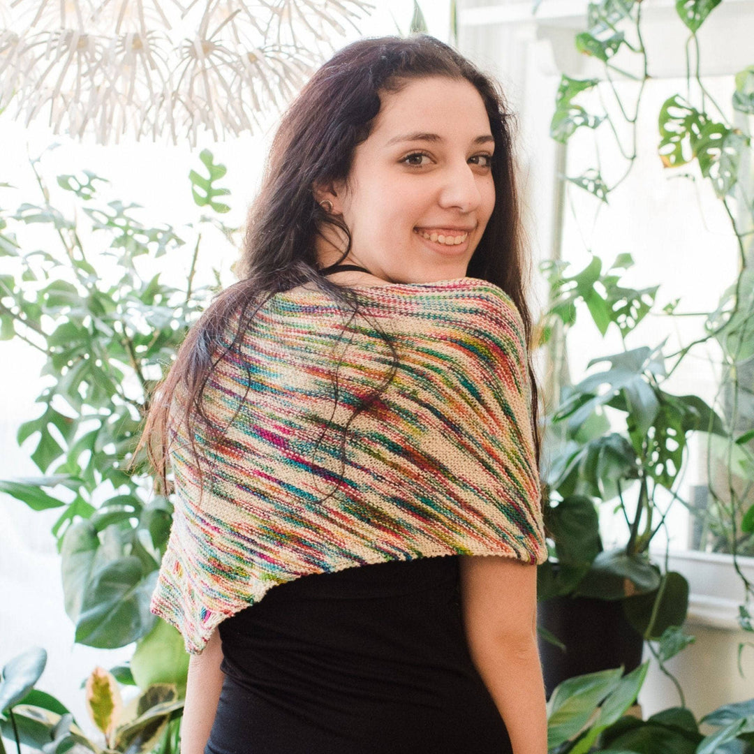 Model wearing unicorn cloud neon pop shawl with potted greenery in the background