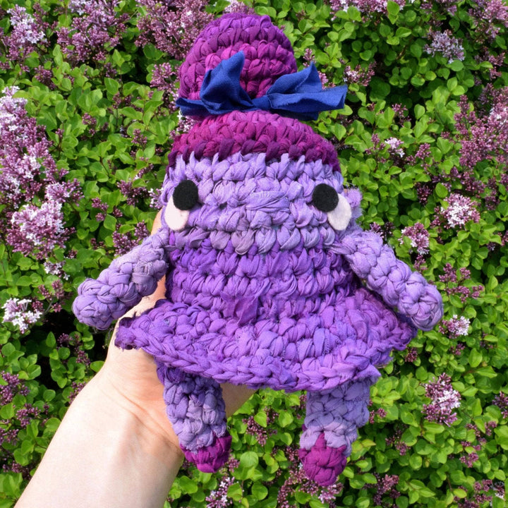 Purple amigurumi sugar plum fairy made of silk chiffon being held by someone outside 