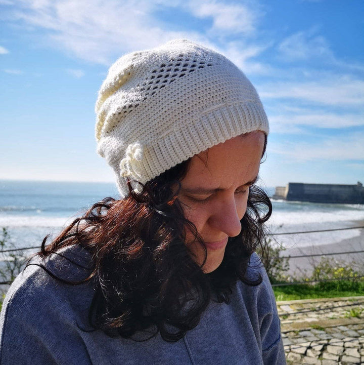 A women wearing a white beanie outside with boats in the background