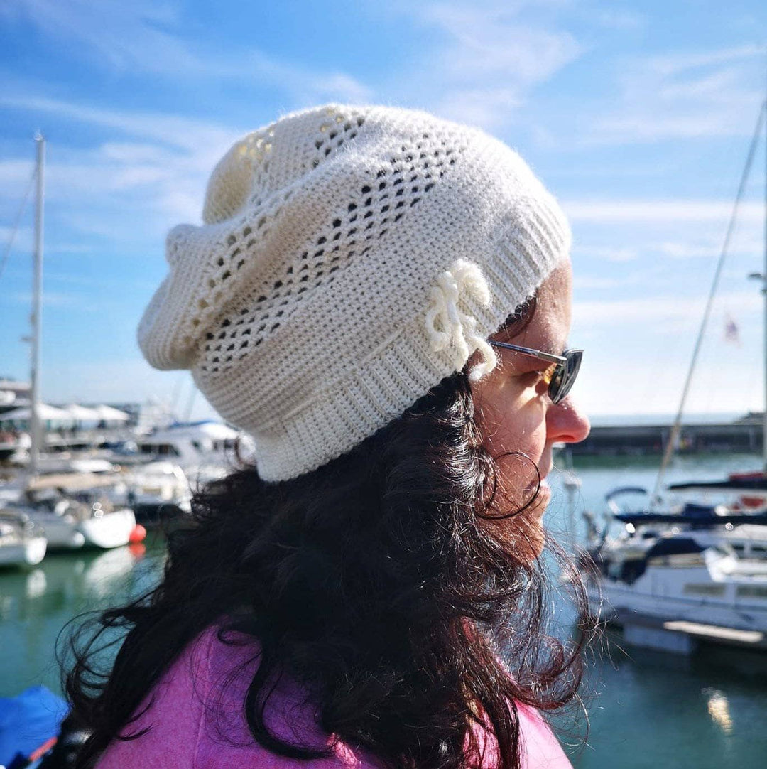 A women wearing a white beanie outside with boats in the background