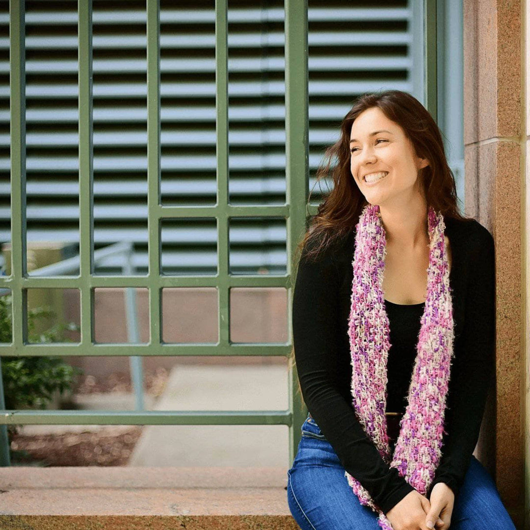 Lifestyle picture of a woman wearing a hand-knitted scarf made from Plant Based Banana Fiber Yarn.  The scarf showcases the unique texture and vibrant colors of the yarn, adding a stylish and eco-friendly touch to her outfit. Perfect for highlighting the versatility and charm of sustainable banana fiber yarn in wearable accessories.