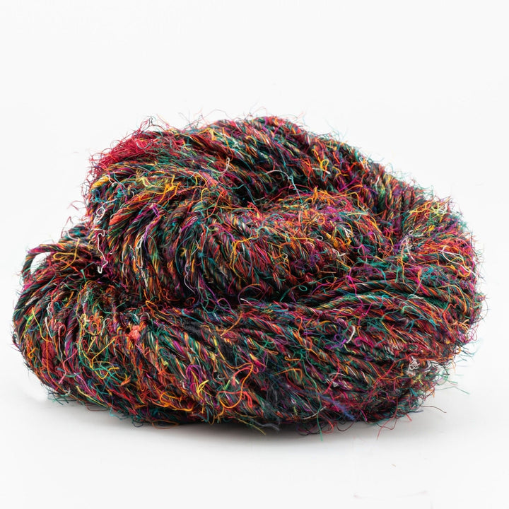 Close-up image of a skein of Plant Based Banana Fiber Yarn, showcasing its vibrant mix of colors including reds, greens, blues, and oranges. The yarn features a unique, textured appearance with charming inconsistencies, making it ideal for knitting, crocheting, weaving, and mixed media projects. Handspun from sustainable banana tree bark fibers, this eco-friendly and biodegradable yarn offers a soft, plant-based alternative reminiscent of silk.