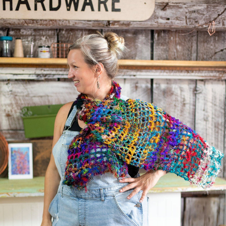 Model wearing quadramesh shawl while smiling with a barn wall in the background.